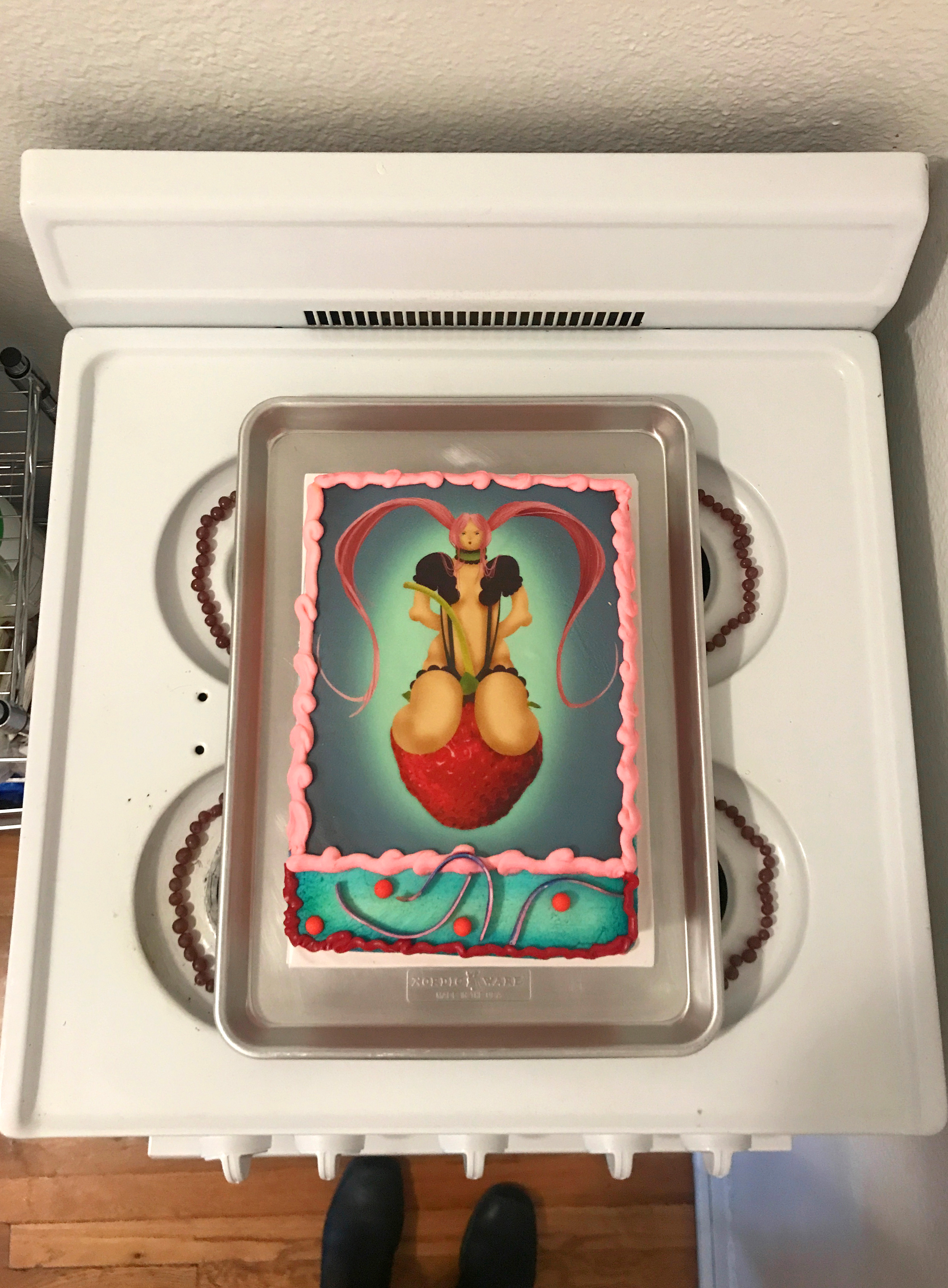 Ariel view of a cake with an illustration of a girl on it atop a stove